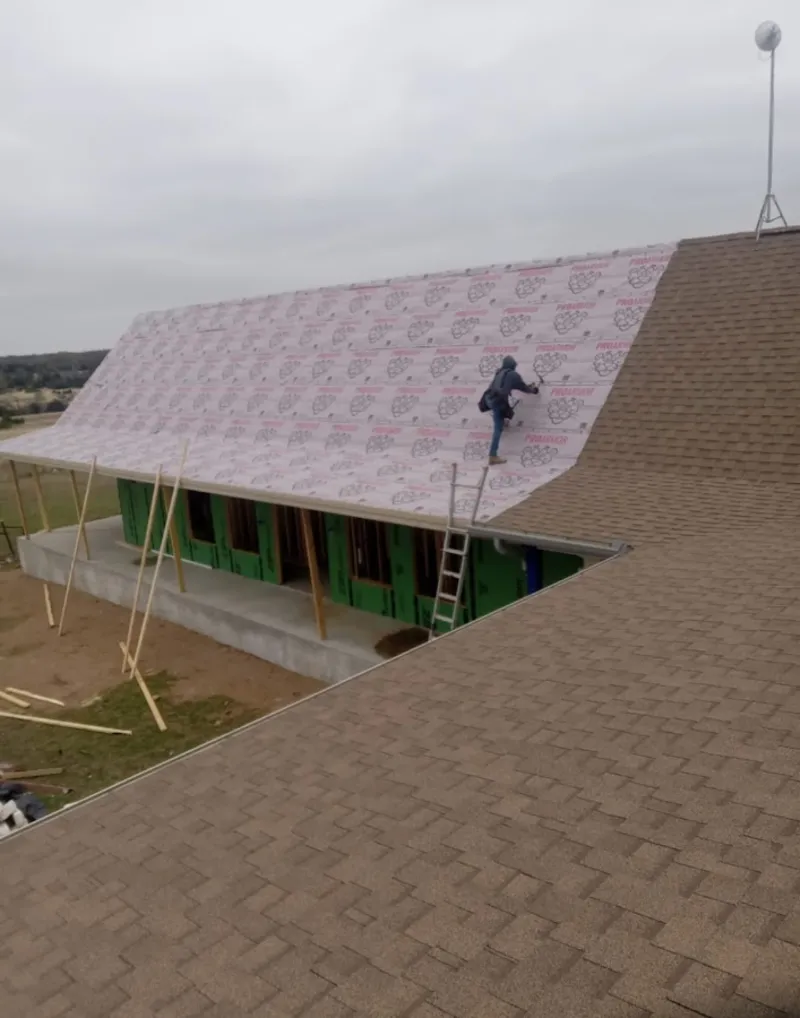 Worker preparing underlayment for a metal roof installation in Mill Creek